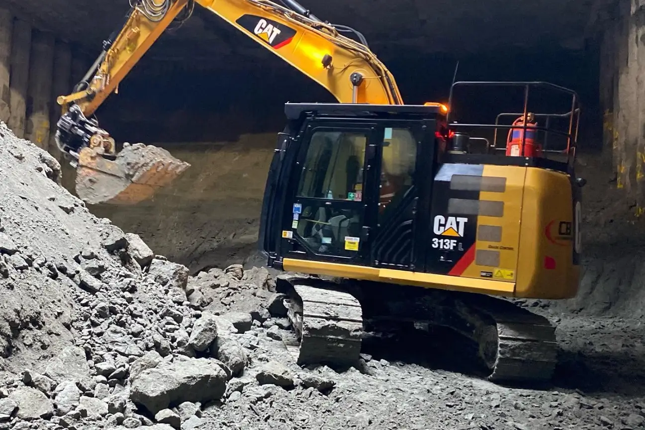 CAT 313FL excavator digging deep underground rock for CB Earthmoving Northland foundation construction.