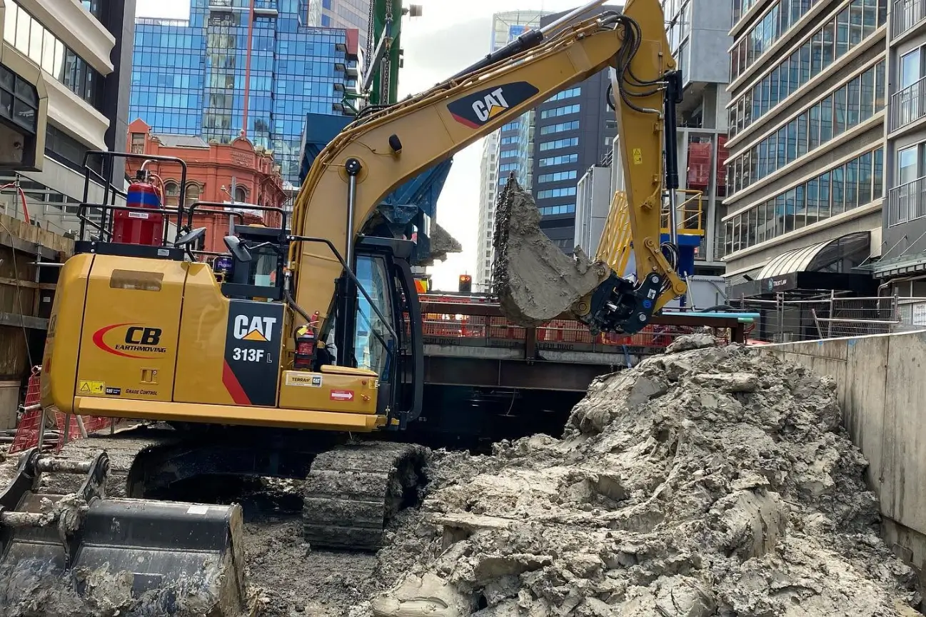 CB Earthmoving Northland CAT 313FL excavator moving earth on a commercial urban construction site.
