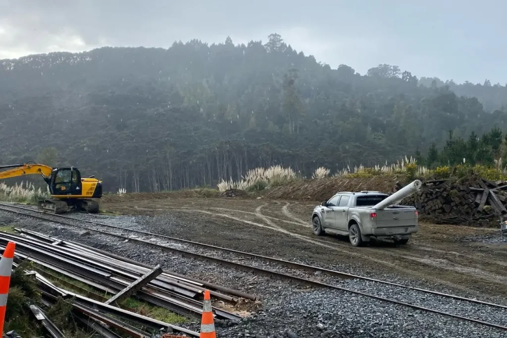 Service ute and excavator stationed on a rural site next to rail tracks for CB Earthmoving Northland property assessment.