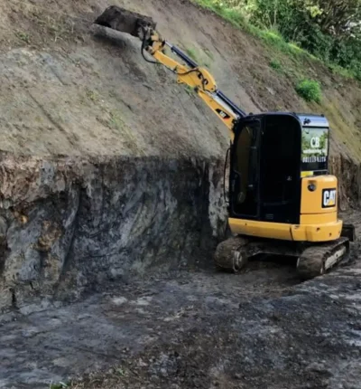 Compact CAT excavator shaping a steep bank for residential and commercial development by CB Earthmoving Northland.